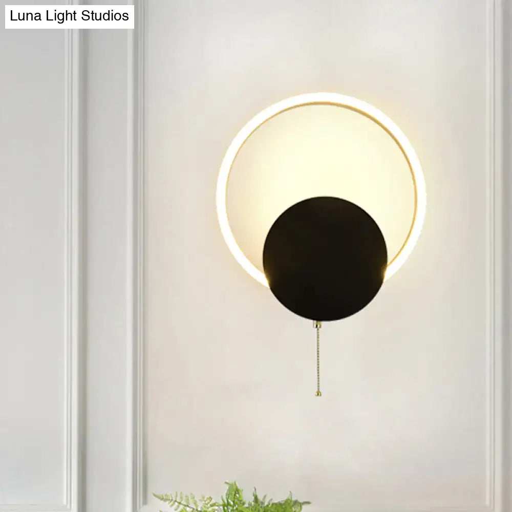Modern black and gold led bedroom sconce with a sleek black disc and brass chain pull 12 inch fixture
