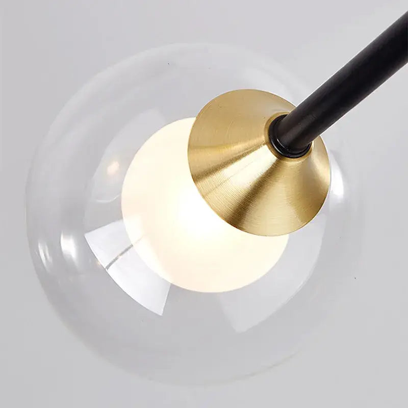 A modern black and gold led chandelier with a clear glass globe and brass metal base for living room decorbites black style