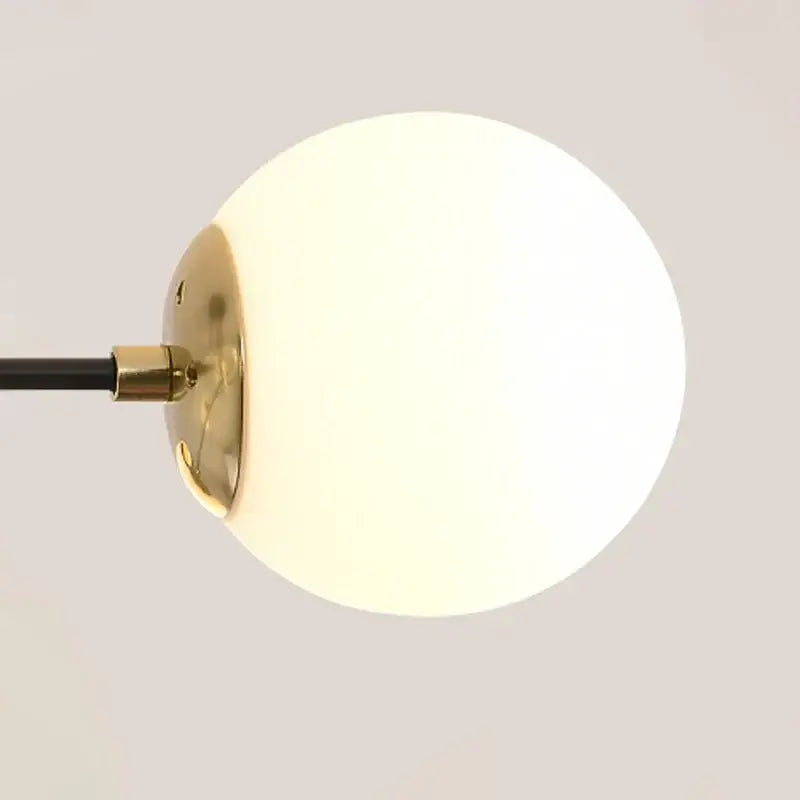 A modern black and gold led chandelier featuring a frosted white glass globe lampshade with a polished brass fixture