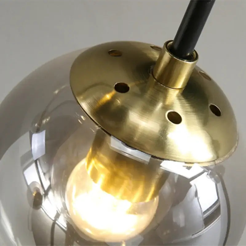 Modern black and gold led round ball chandelier featuring a warm-toned brass pendant light with clear glass globe and filament bulb