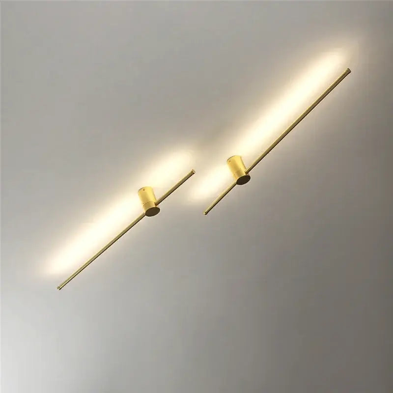 Two sleek gold-toned decorbites led wall lamps with cylindrical fixtures provide warm lighting for minimalist living room decor