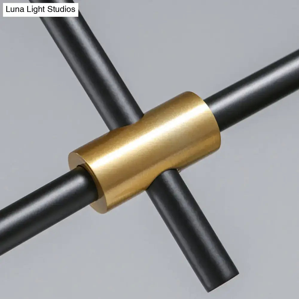 Brass-colored cylindrical connector joining intersecting black rods of a gold black metal cone island light fixture