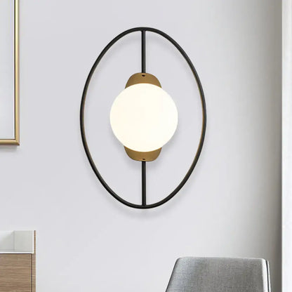 Modern oval wall lamp with black and gold metal halo ring frame and white glass globe for bedroom lighting