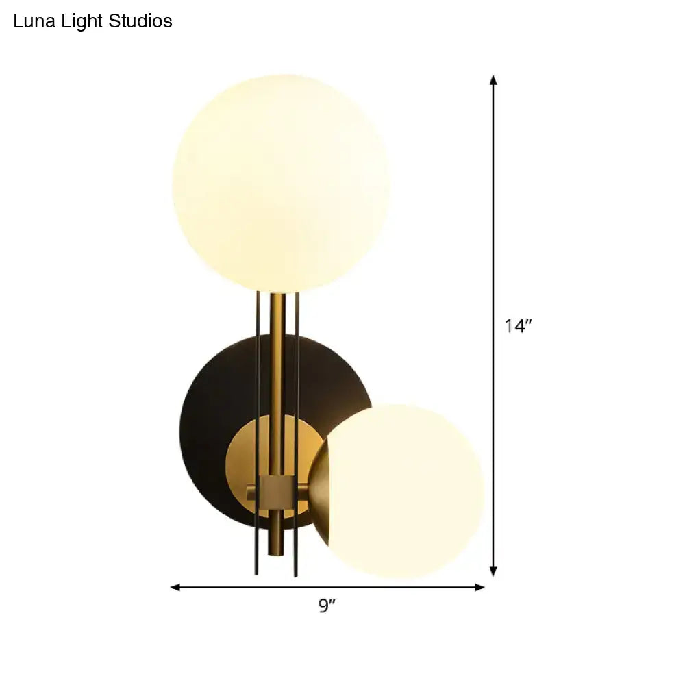 Modern black and gold two-globe wall light with brushed brass finish and milky glass shades direct wired electric