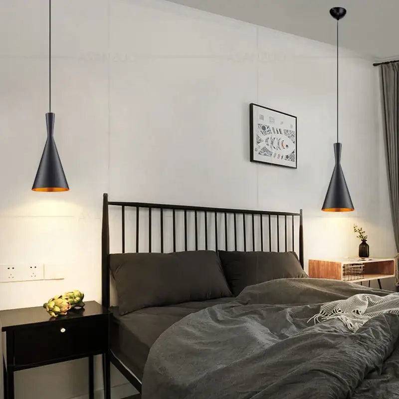Modern black and gold musical pendant light with conical gold interiors hanging above the bed in dining room