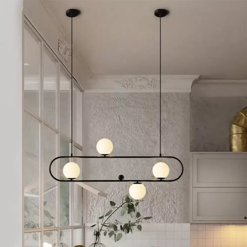 Modern black gold metal pendant light with four frosted opal glass globe bulbs for dining room ceiling lighting