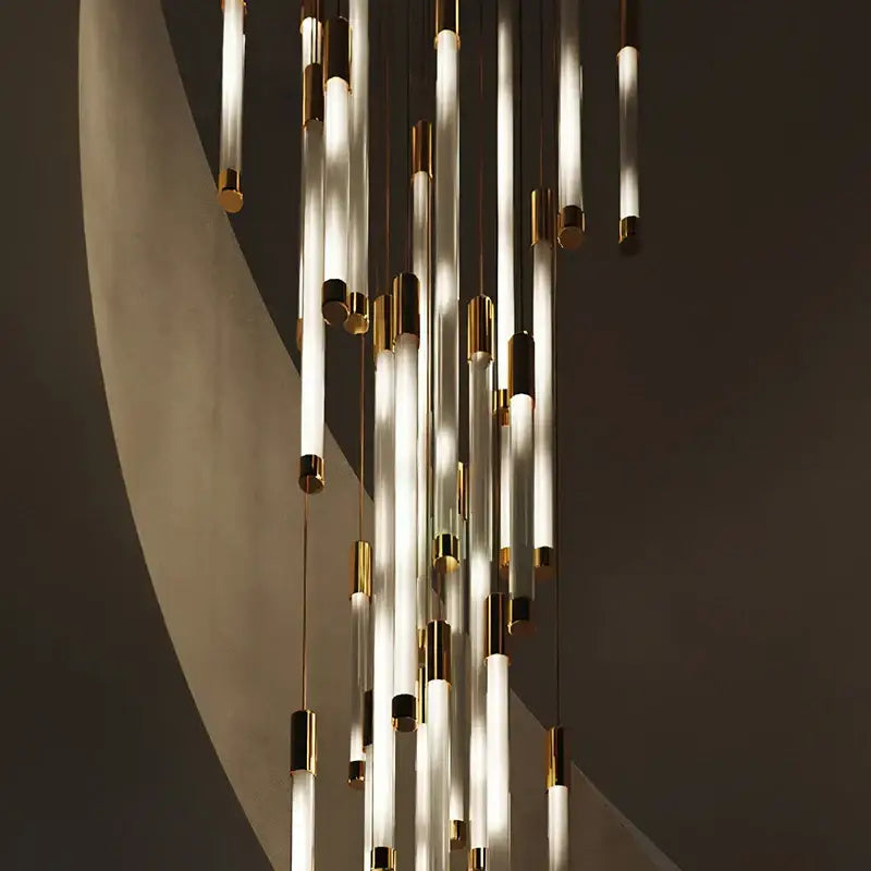 Modern black and gold pendant chandelier with translucent glass tubes and polished metal caps as a staircase pendant light