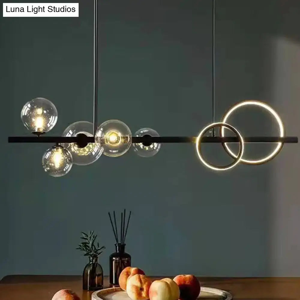 Modern black metal pendant light with clear glass spheres and gold rings on black metal bar for dining room