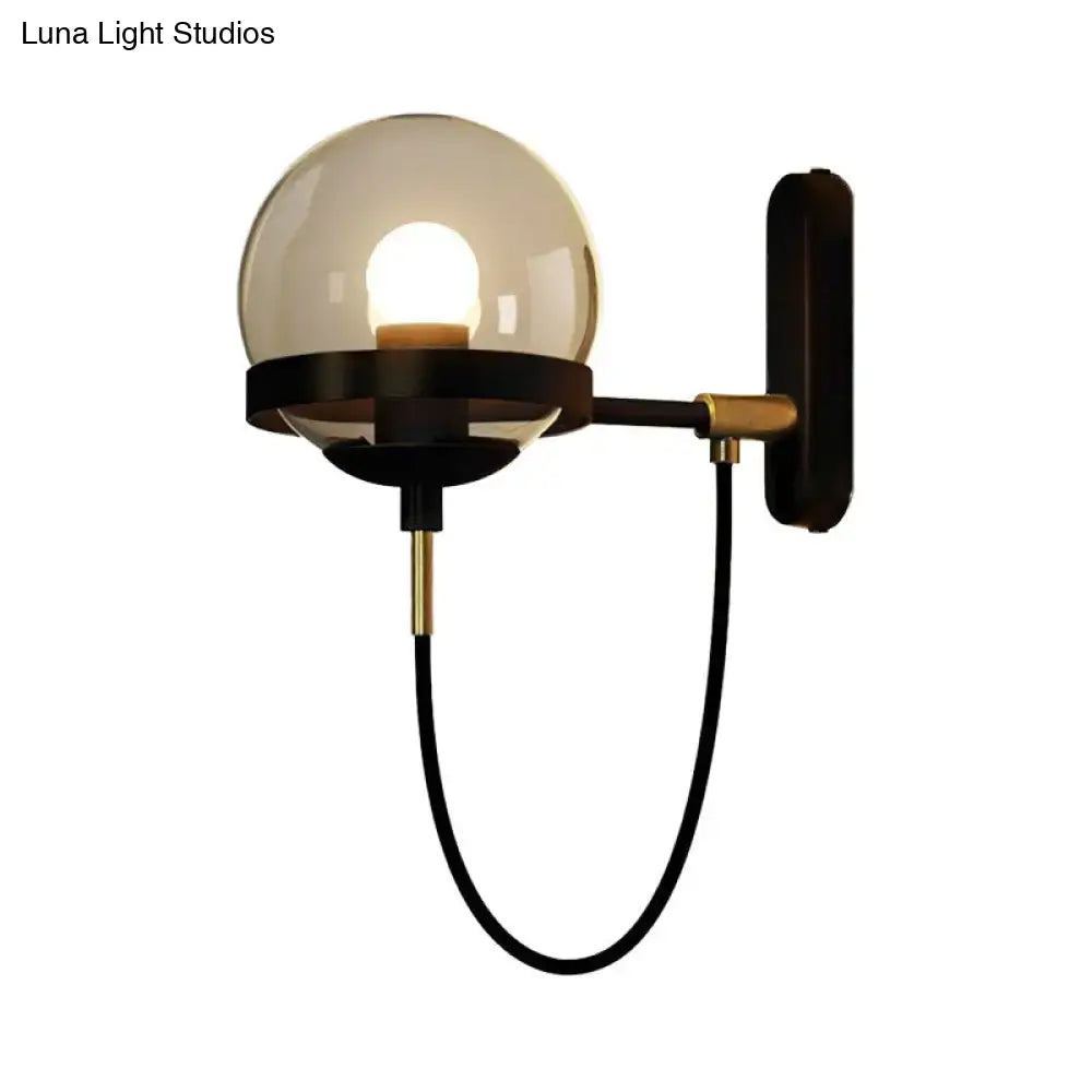A modern black gold wall lamp featuring a sleek brass frame and a smoke glass globe for living room ambiance