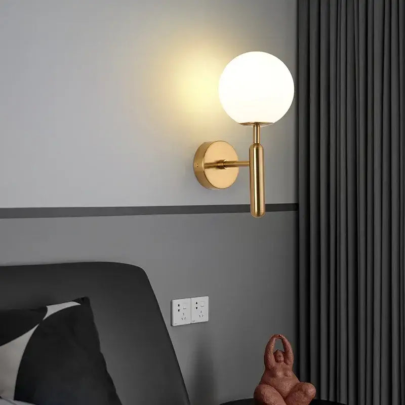 Gold-toned led wall sconce with frosted glass globe and modern black and gold teardrop design for bedroom lighting