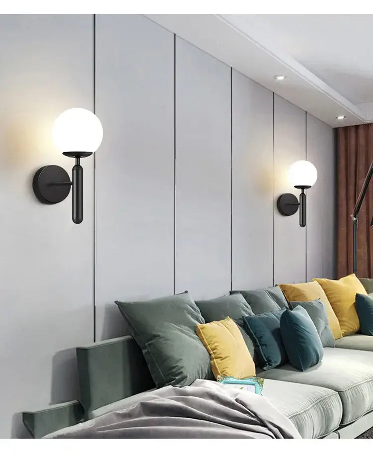 Modern black and gold led wall sconce featuring a spherical white glass globe for bedroom lighting