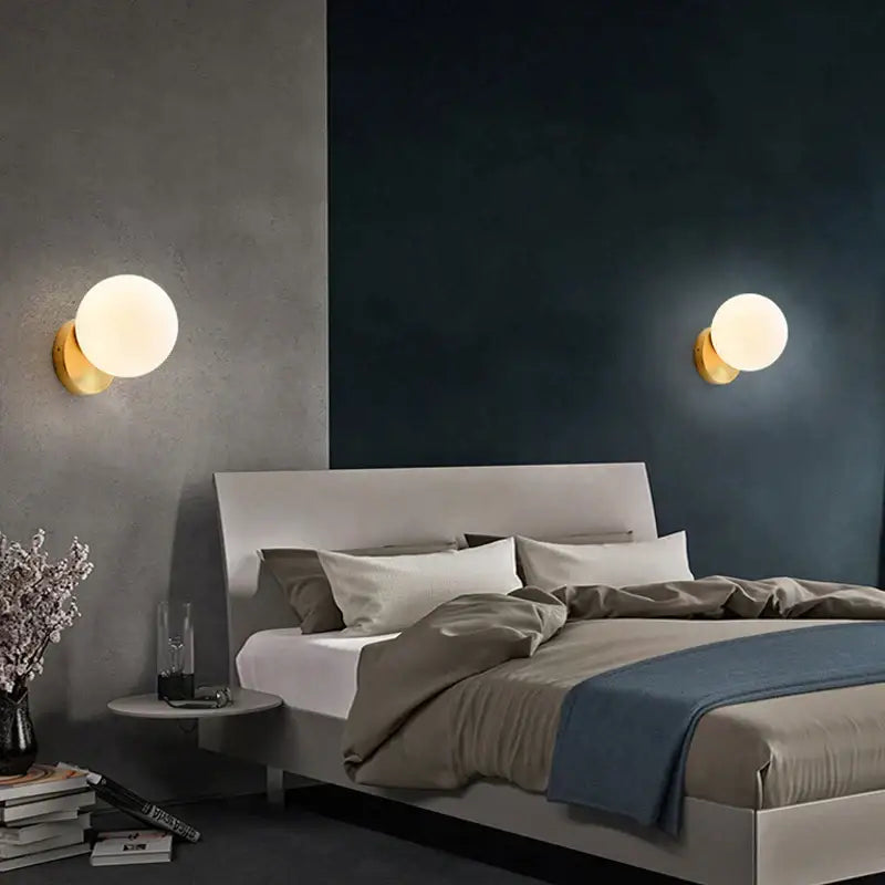 Pair of modern black and gold teardrop led wall sconces with glass globe and warm glow for bedroom lighting
