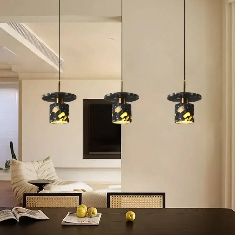 Three modern pendant lamps with black terrazzo stone textured ceramic shades and brass accents for kitchen decorbites black terrazzo