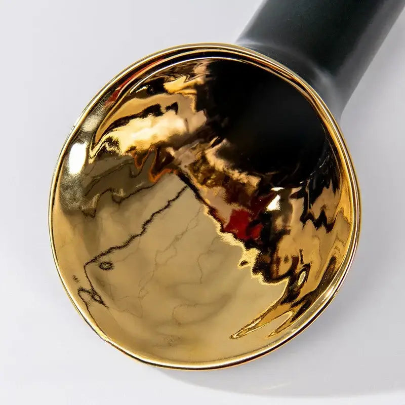 A glossy gold ceramic bowl with a crackled interior and black handle from the decorbites golden trumpet vase set