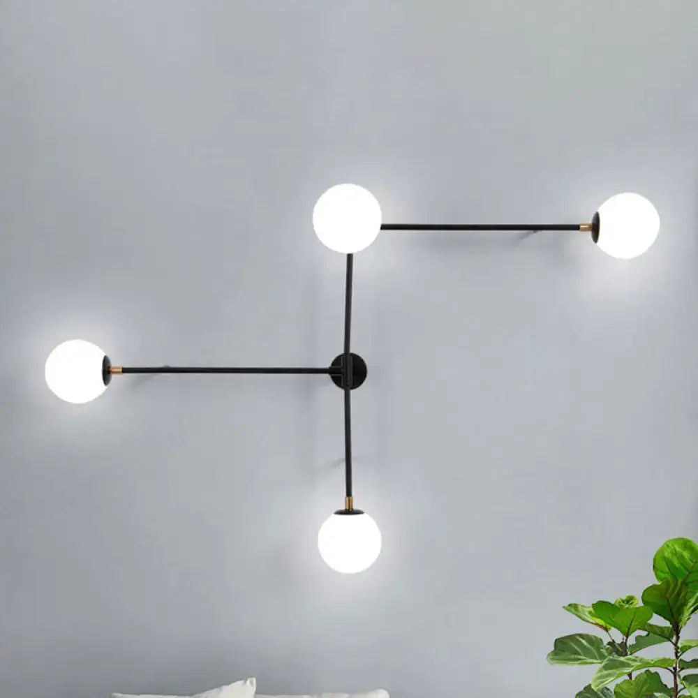 Modern black metal wall lamp with gold accents and three glowing white glass bulbs in direct wired electric design