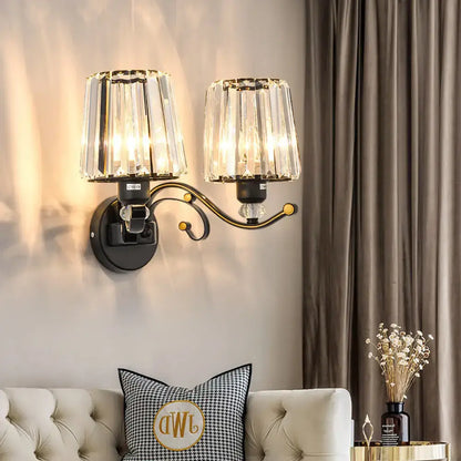 Modern black and gold wall lamp with clear glass crystal lights and ornate curved arm for bedroom sconce lighting