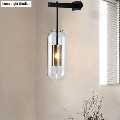 Modern black and gold wall mounted light featuring a clear glass cylinder and gold-toned perforated accent for living room use