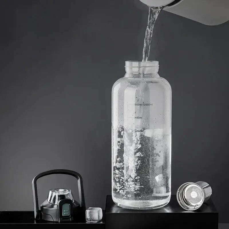 Modern black and green decorbites glass cup with clear glass water bottle, measurement markings, black lid, and metal filter