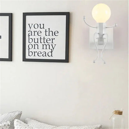 White whimsical wall sconce with articulated arms and legs holding a bulb decorbites cartoon doll wall sconce for kids bedroom