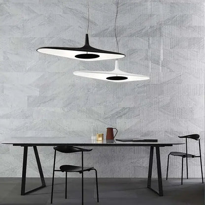 Two modern black irregular art pendant lamps with sleek disc-shaped designs hang above a dining table decorbites irregular art pendant