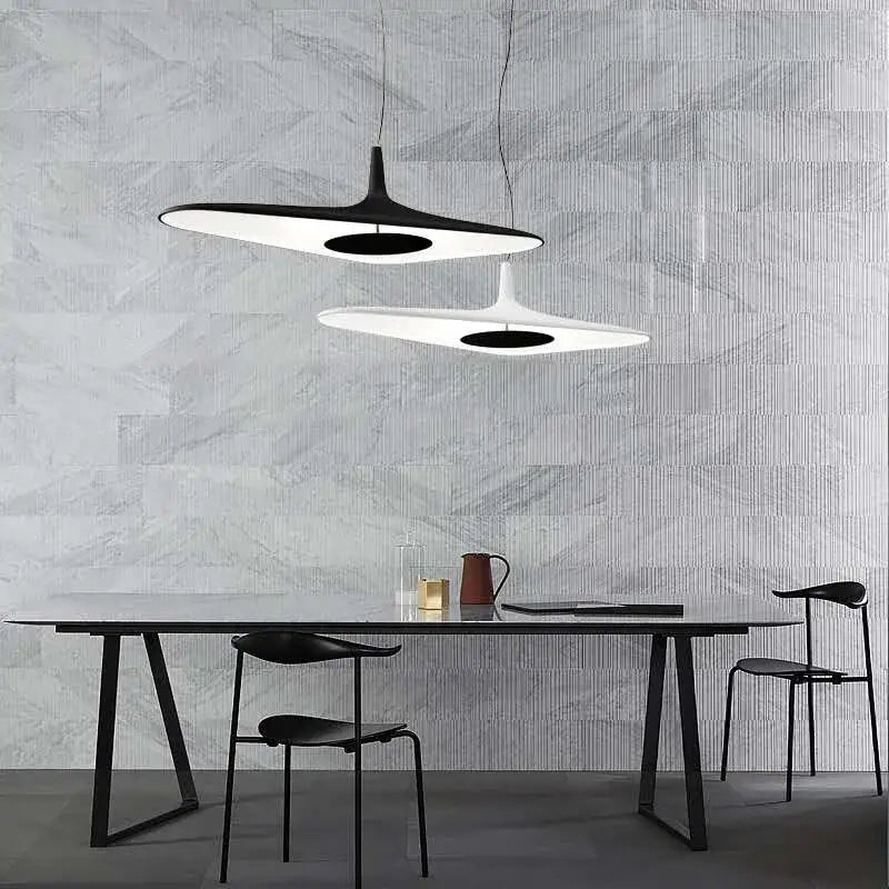 Two modern black irregular art pendant lamps with sleek disc-shaped designs hang above a dining table decorbites irregular art pendant