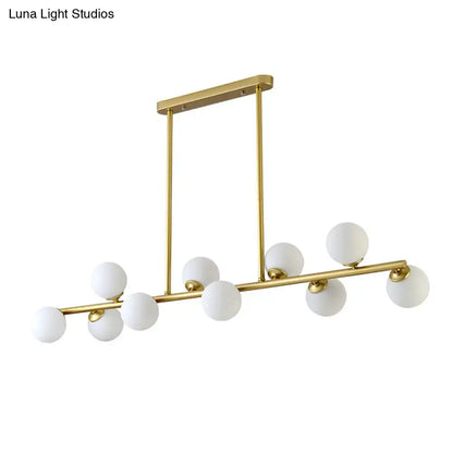 Modern gold-toned modo island ceiling light with nine frosted glass globe bulbs on a sleek rectangular mount for dining rooms