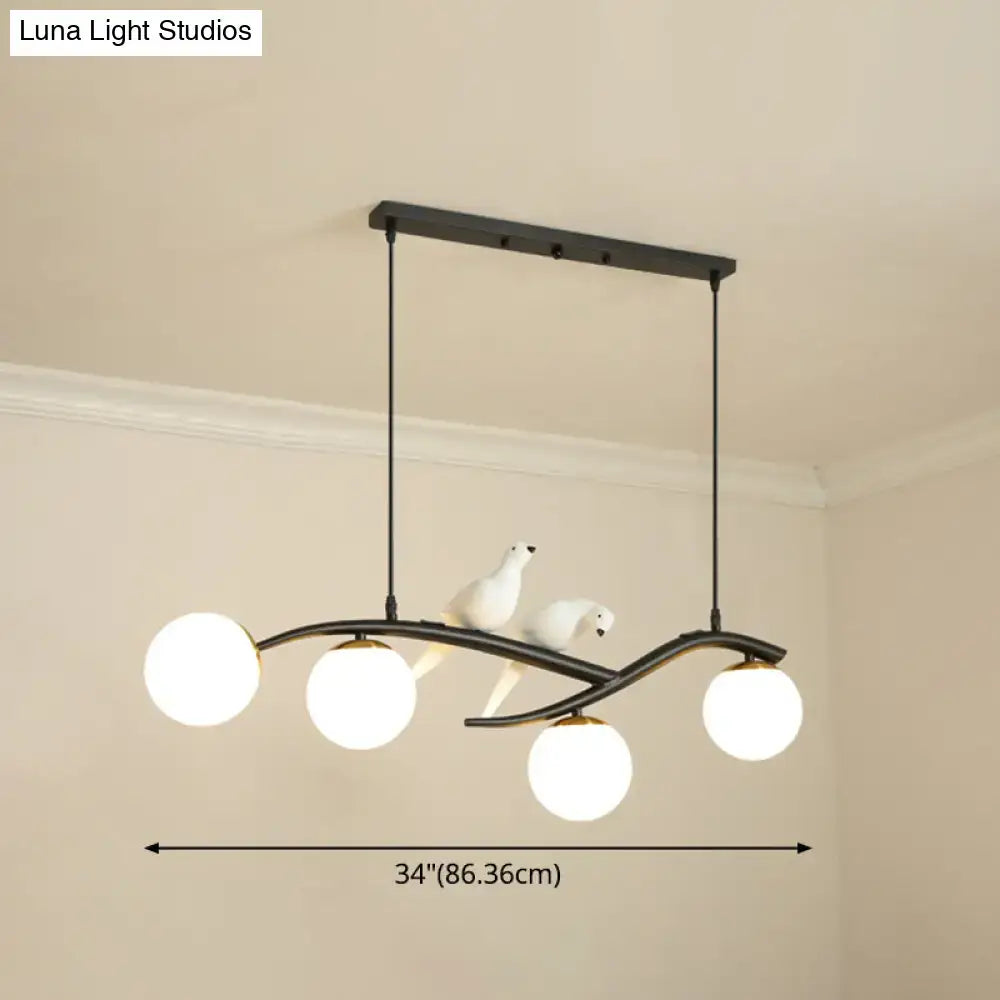 Black metal pendant light with four white frosted glass globes and two white ceramic bird figurines on curved arms