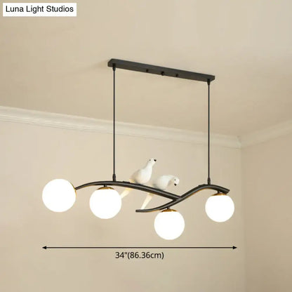 Black metal pendant light with four white frosted glass globes and two white ceramic bird figurines on curved arms