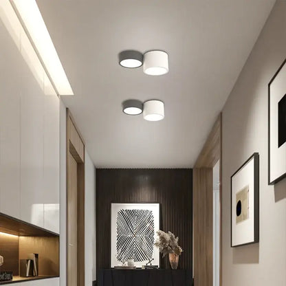 Two modern recessed led ceiling lamps with white cylindrical shades and dark gray bases for living room use