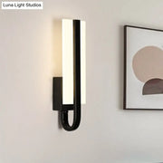 Modern black metal sconce light fixture with sleek curved design and glowing white warm light panel for living room
