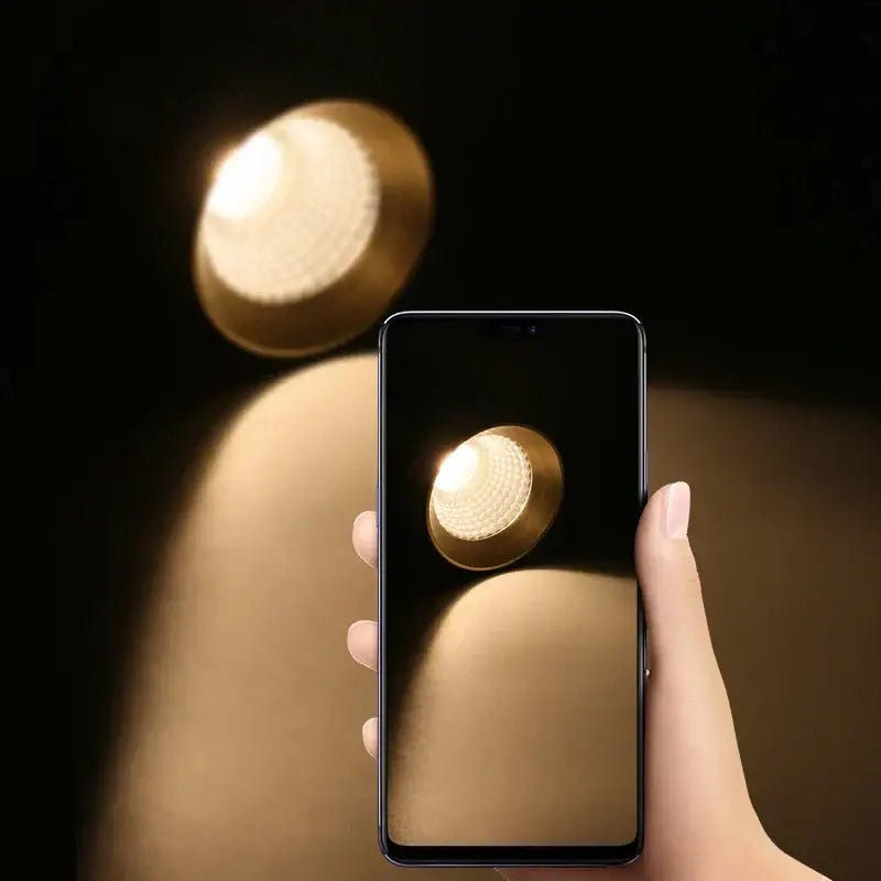A sleek black smartphone displays a golden textured bulb for the modern black led track spotlight kitchen ceiling lamp