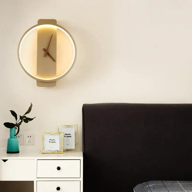 Modern black led wall clock lamp with warm led ring and minimalist wooden face mounted on white wall for living room use