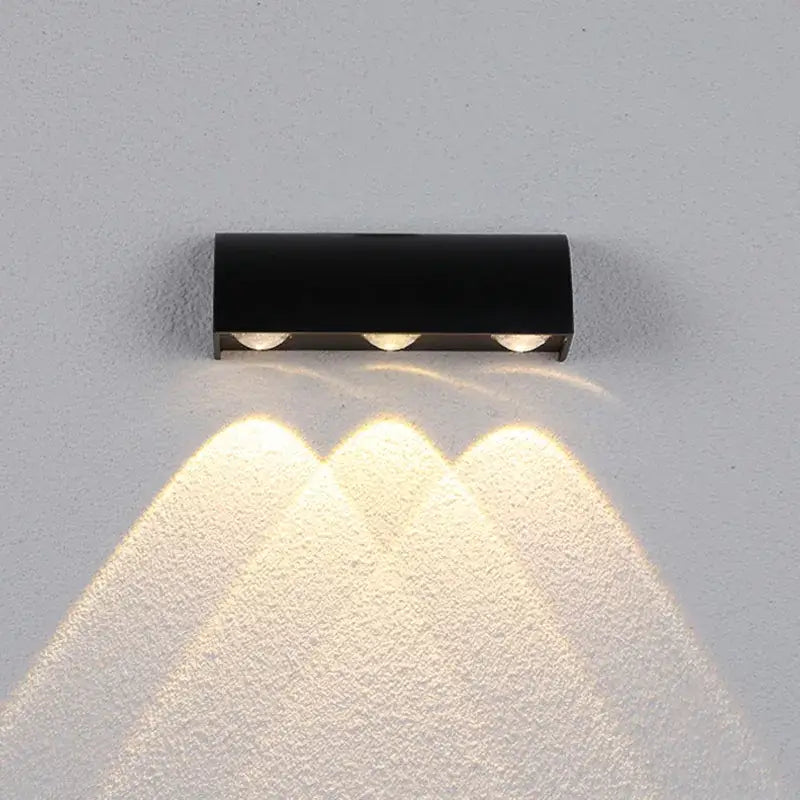 Modern black led wall lamp with three warm white bulbs emitting focused beams in a sleek rectangular lighting fixture