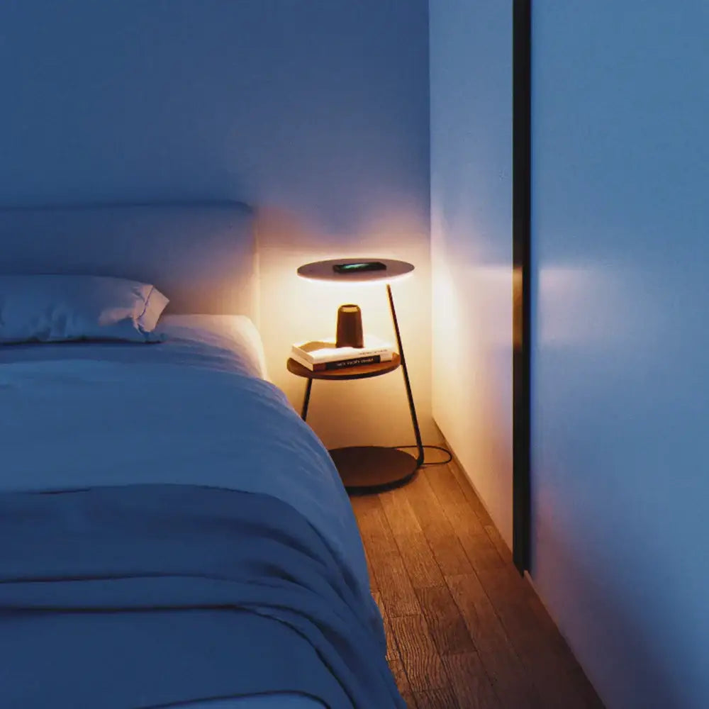 Minimalist round side table with wooden top and black metal legs illuminated by warm light from decorbites led wood floor lamp