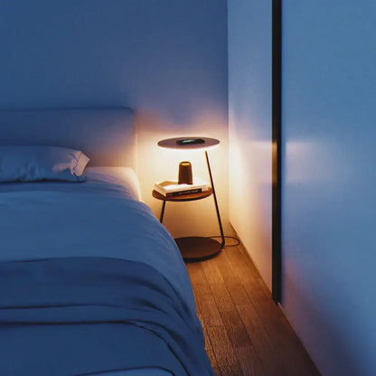 Minimalist round side table with wooden top and black metal legs illuminated by warm light from decorbites led wood floor lamp