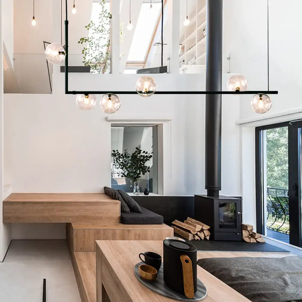 Black ceramic kettle with wooden handle on gray tray under modern black linear island pendant with glass shade in dining room