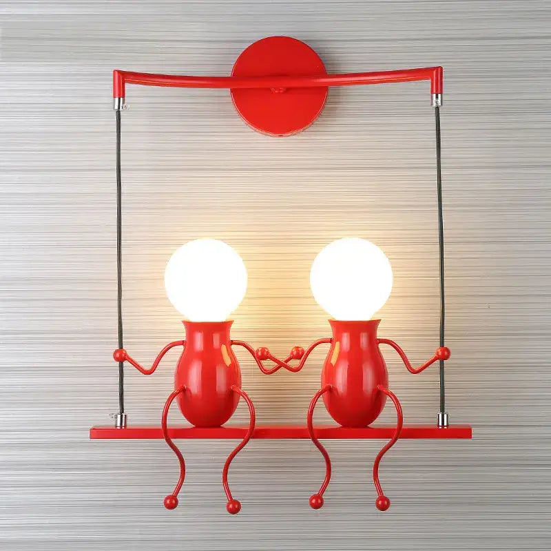 Modern black man led wall light featuring red metal sconce with two figurine holders and glowing spherical bulbs