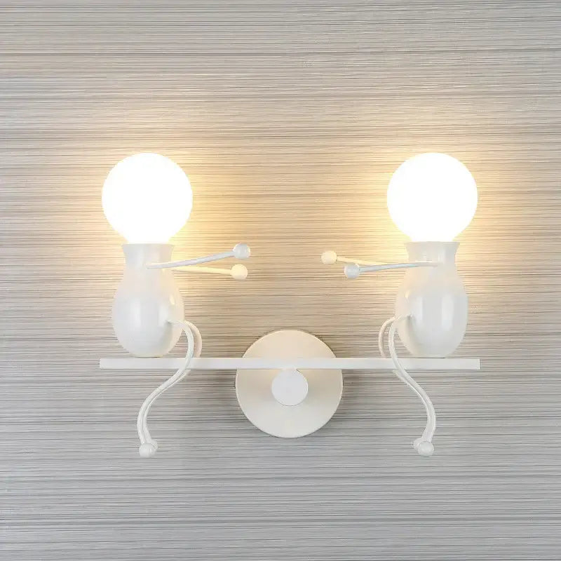 White wall-mounted sconce with two black whimsical man led wall light figurines featuring spherical bulbs and curved limbs
