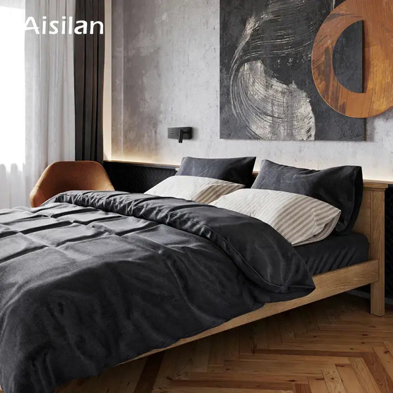 Dark gray velvet duvet set on light wood bed frame illuminated by modern black matte led wall sconce reading light