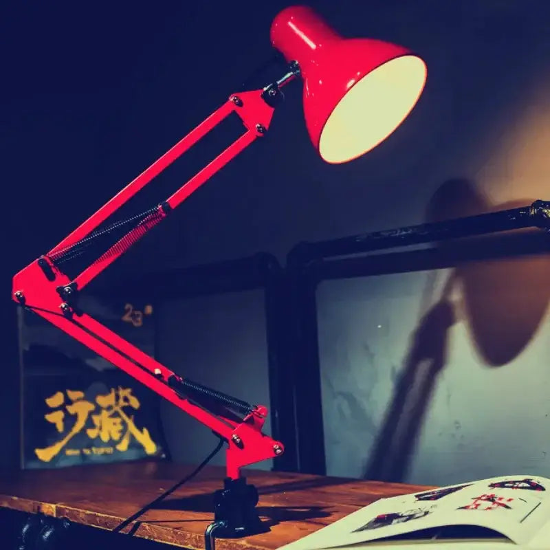 Vibrant red desk lamp with adjustable swing arm and black metal joints in a classic industrial design