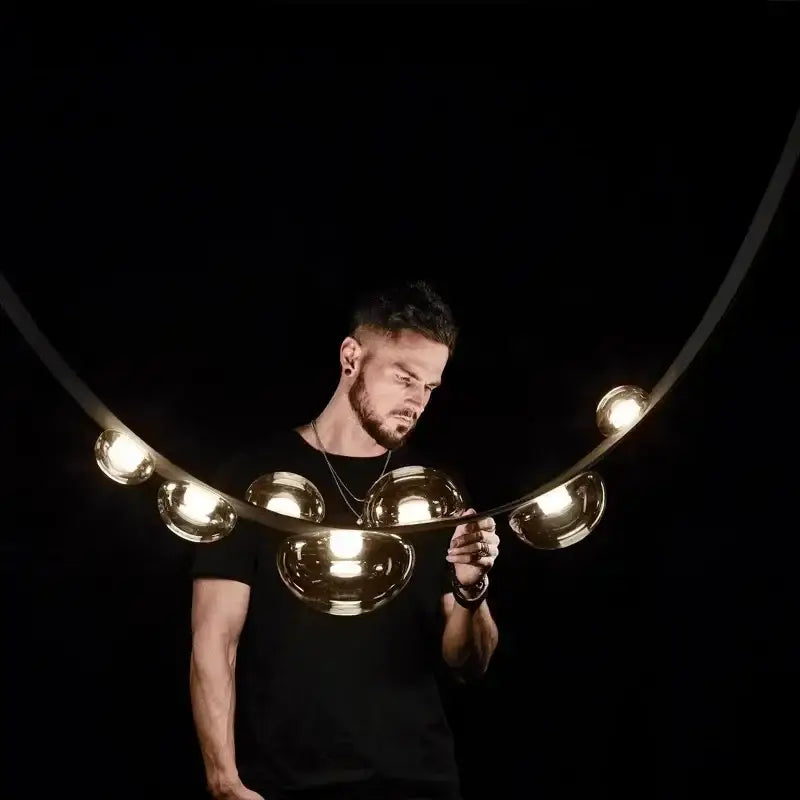 A sleek curved golden metallic pendant light with multiple spherical bulbs for modern decorbites designer leather loft decor
