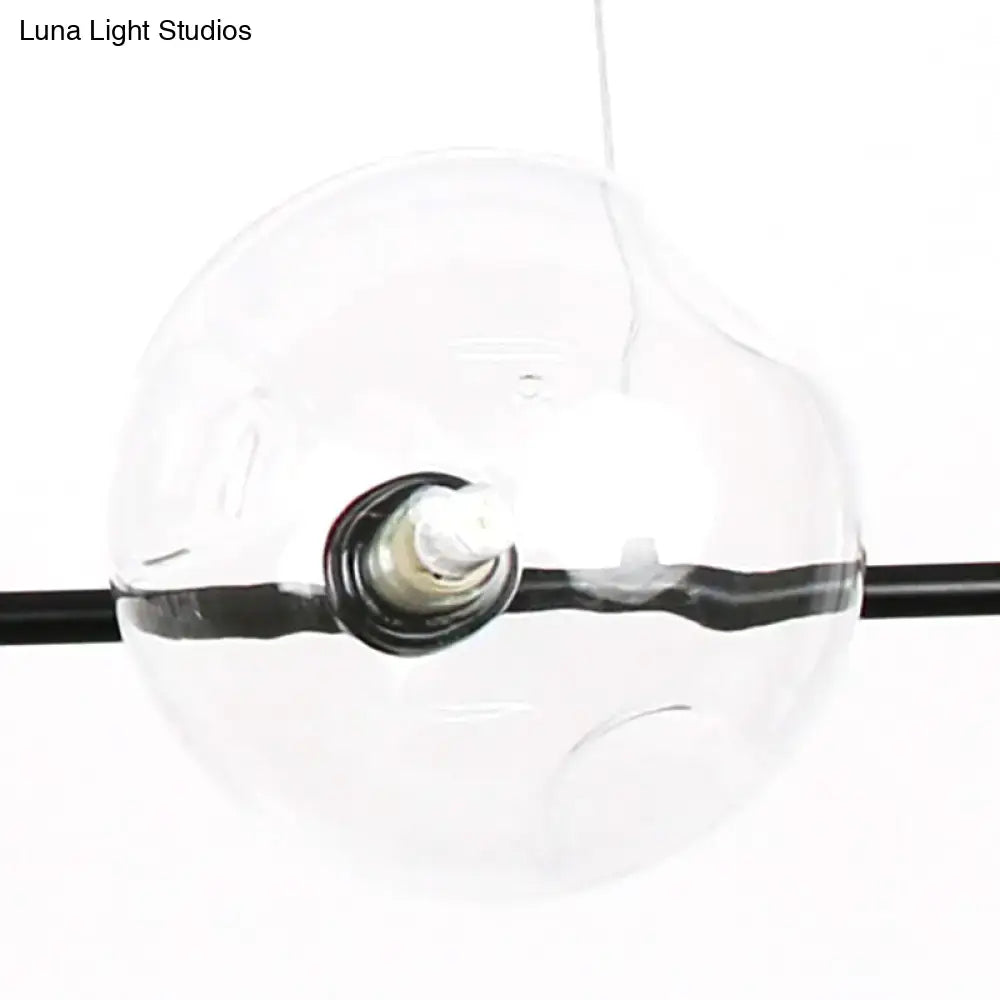Clear glass globe pendant light with black horizontal band and visible bulb base in modern black metal chandelier design