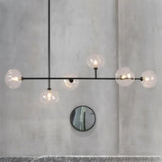 Modern black metal chandelier with five clear glass globe bulbs and bulb base for stylish restaurant ambiance lighting
