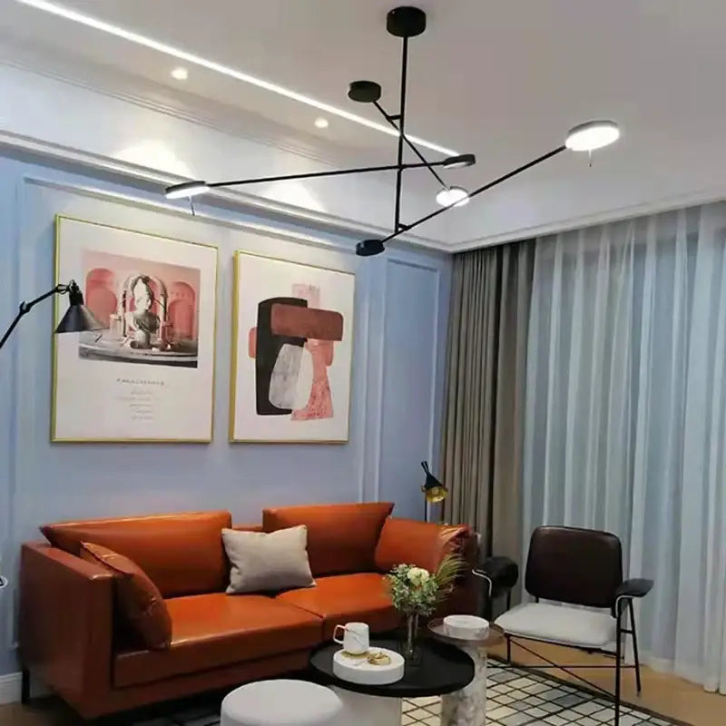 Modern black metal led chandelier with spherical light above orange leather sofa and light gray throw pillows decorbites black metal