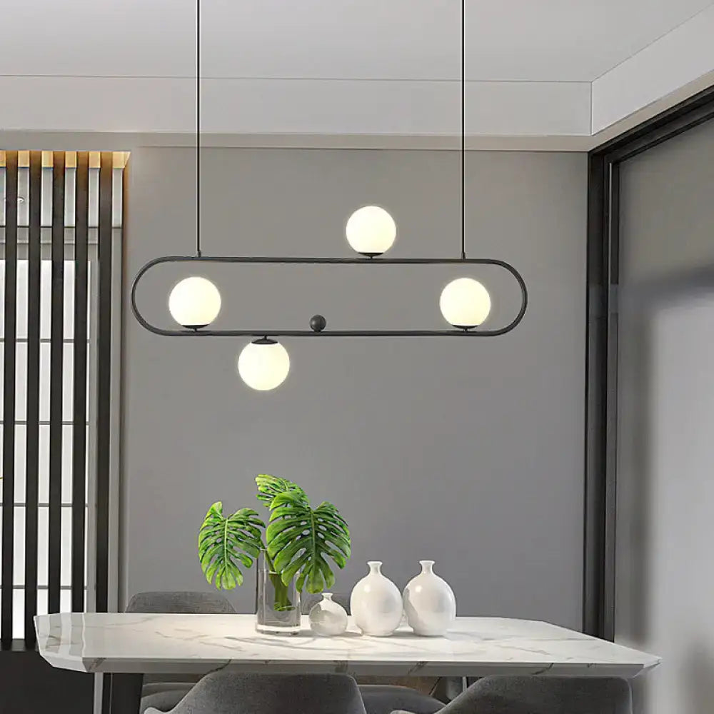 DecorBites™ minimalist black metal oblong island light fixture with four glowing white milk glass spherical bulbs