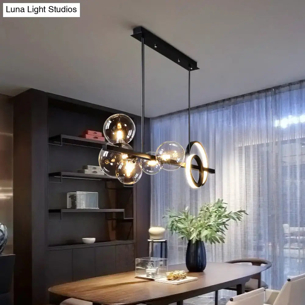 Modern black metal pendant light fixture with glass globe and circular accent suitable for dining room ceiling light