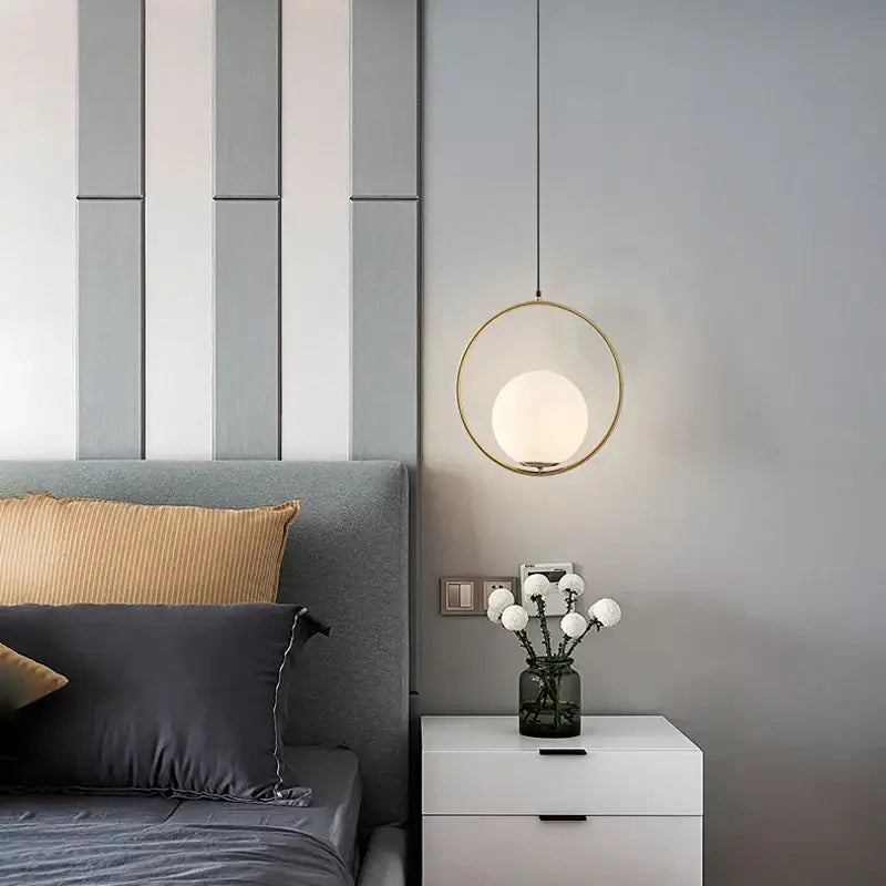 Minimalist pendant light with a black metal ring frame and gold-toned frosted glass globe for dining room use