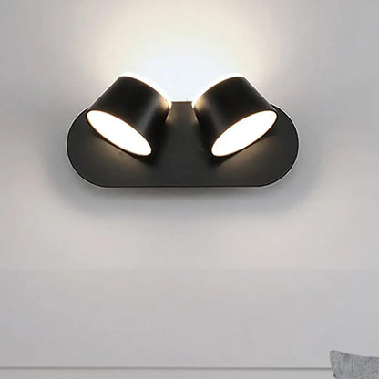 Modern black metal shade wall sconce with dual-head spotlight featuring sleek design and compact fixture width and shade height
