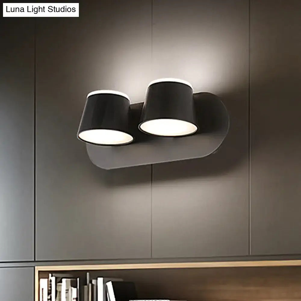 Modern black metal shade wall sconce with two cylindrical shades and sleek curved base for bedroom vanity fixture