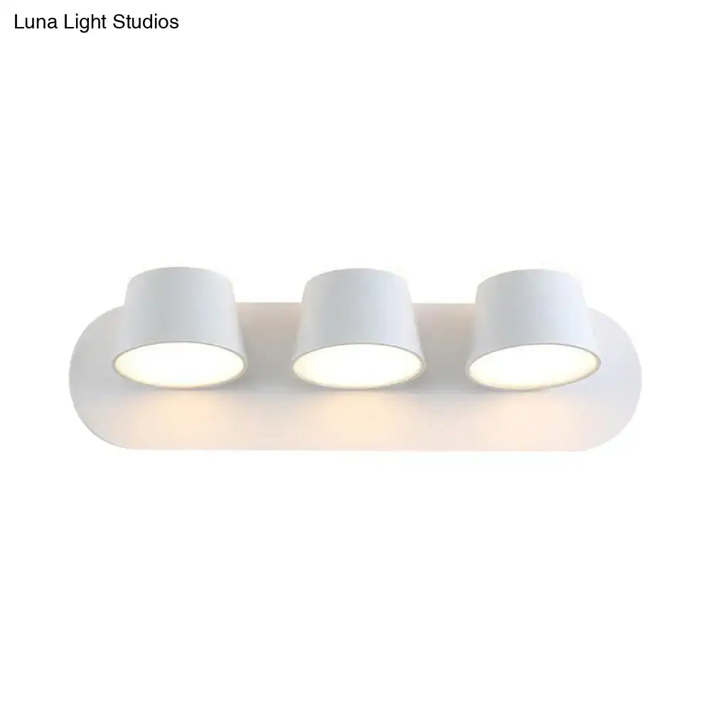 White minimalist wall-mounted fixture with three cylindrical metal shade lamps for bedroom vanity use with shade height details